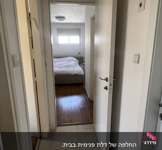 דלת פתוחה מובילה לחדר שינה עם מיטה